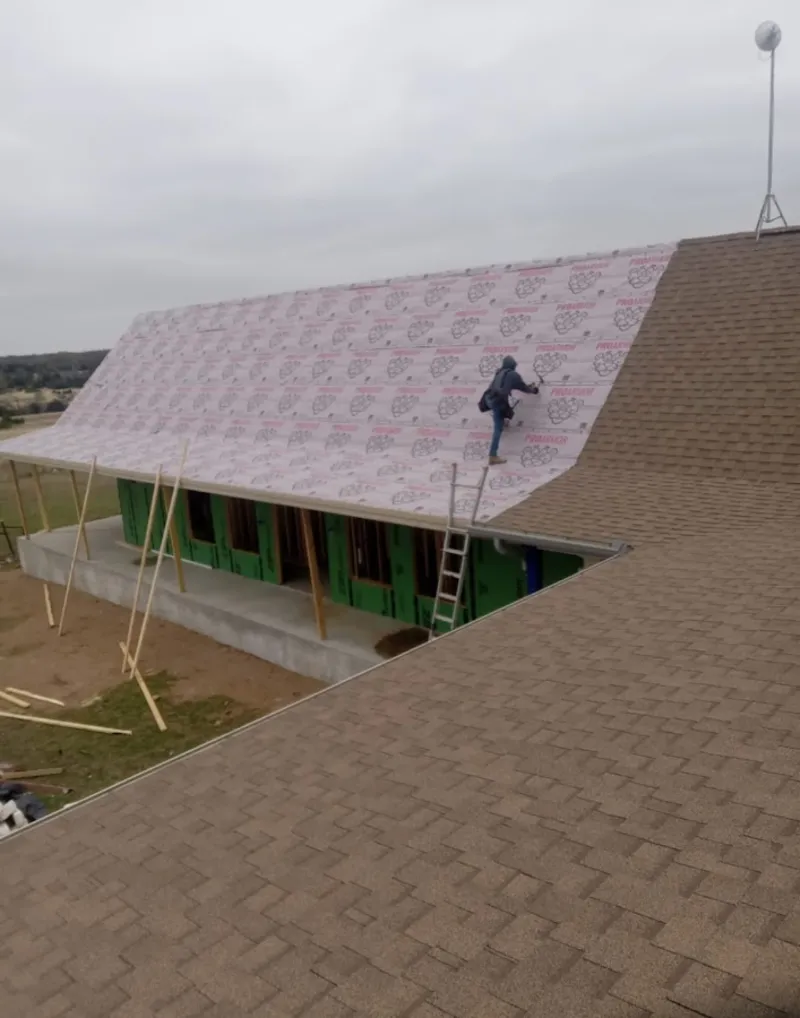 Worker preparing underlayment for a metal roof installation in Martha Lake